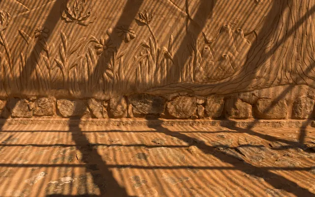 A relief of grasses carved into an earth-plastered wall