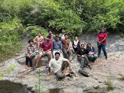 Retreat participants sitting together on the rocks of a stream bed