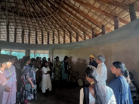 Students gathered inside a round earth-walled hall under a radiating timber roof