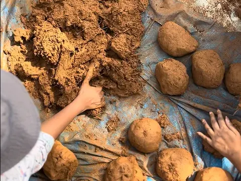 Hands shaping balls of the hill's own clay on a tarpaulin